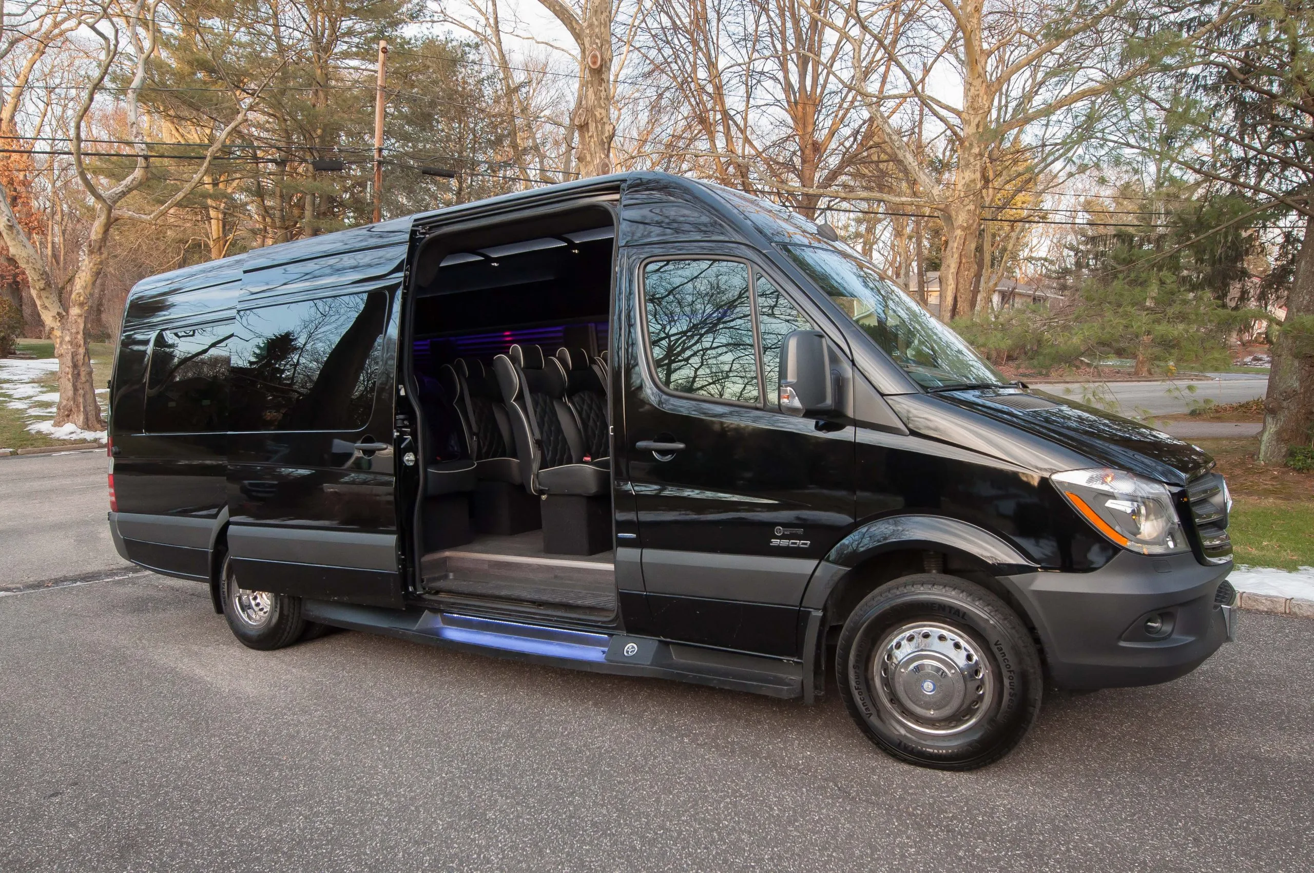 A luxury black Mercedes-Benz Sprinter 3500 passenger van with the side door open, revealing premium executive leather seating for charter mini bus rentals Toronto.